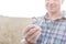 Midsection of mature farmer examining wheat at farm