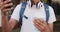 Midsection of mixed race man drinking coffee and using smartphone in the street