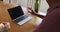 Midsection of mixed race man sitting at table making video call with laptop and waving