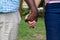 Midsection of multiracial senior couple holding hands in backyard