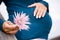 Midsection of pregnant woman holding pink flower