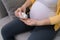 Midsection of pregnant woman pouring pills in hand from bottle at home