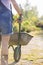 Midsection rear view of female gardener pushing wheelbarrow at plant nursery