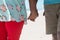 Midsection of retired african american senior couple holding hands at beach