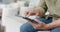 Midsection of senior biracial man sitting on table using tablet at home, slow motion