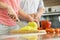 Midsection of woman chopping vegetables in kitchen with man standing in background