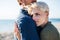 Midsection of young couple standing outdoors on beach, hugging. Copy space.