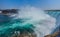 Mighty Niagara River roars over the edge of the horseshoe falls in Niagara Falls Ontario. Misty foggy spray rises up.