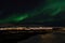 Mighty northern light dancing over snowy mountain peak in northern norway on the whale island settlement