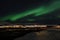 Mighty northern light dancing over snowy mountain peak in northern norway on the whale island settlement