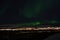 Mighty northern light dancing over snowy mountain peak in northern norway on the whale island settlement