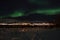 Mighty northern light dancing over snowy mountain peak in northern norway on the whale island settlement underneath