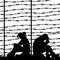 Migrant refugees behind barbed wire, silhouette of a pair of sad