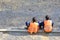 Migrants workers in yellow and orange vests resting by the road. They are sitting on the sidelines. Repair the road. Copy space.