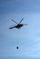 Mil Mi-17 helicopter flies in the sky carrying bucket of water for fire fighting purposes