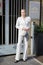 MILAN, ITALY - FEBRUARY 25, 2023: Woman with white jacket and trousers with white flower before Ermanno Scervino fashion show,