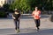 Milan, Italy - May 8, 2020: Runners women exercising running on athletic track outdoor wearing medical mask. Sport practice