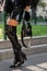 Milan, Italy - September, 22, 2022: woman wearing black varnished bag, over the knees boots and skirt, street style