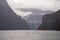 Milford Sound fjords, surrounded by majestic mountains and dramatic clouds.