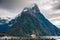 Milford Sound and Mitre Peak, South Island, New Zealand. Steep sided mountains rise from calm waters of the fiord with moody sky