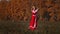 Militant concept on an autumn field - woman in red national dress training her swordplay