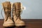 Military boots with flower on wooden surface,  for text. Armed Forces Day