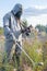 Military dosimetrist measures radiation on a grassy area. chemical protective SUIT and gas MASK, Sunny day