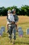 Military father in cap holding in ams kid in straw hat near headstones