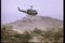 Military helicopter flying over men on horseback in desert