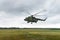 Military helicopter preparing to take off from grassy field on the background of the city