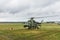 Military helicopter preparing to take off from grassy field on the background of the city