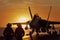 A military jet standing on a sailing navy aircraft carrier during sunset.