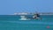 Military landing boat quickly floats on blue surface of sea leaving traces of foam on background of shore