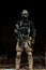 Military man in black uniform with machinegun. Soldier stand in the broken building. Vertical photo