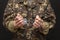 A military man in handcuffs holds an army badge in his hand on a dark background, selective focus. Concept: war criminal, prisoner