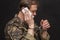 A military man in handcuffs makes a phone call on a dark background, selective focus. Concept: prisoner of war talking on the phon