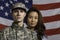 Military man and his wife in front of US flag, horizontal