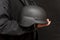 A military man holds an army helmet in his hand, black background. Concept: volunteer at war, war in Ukraine, civil self-defense,