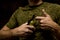 military man holds a grenade in his hands, pulls the pin out of a grenade, black background, anti-personnel grenade