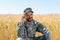 Military man touching cap and smiling in field