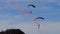 Military paratroopers descending near a mountain full of spectators