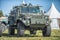 Military patrol car on a green grass. Army war concept. Image of armored vehicle with gun in action.