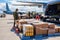 Military personnel at the airfield load boxes and containers with military uniforms and weapons.