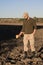 Military sapper with a metal detector examines the soil in the field for the presence of mines