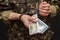 A military soldier or officer in handcuffs holds bundles of dollar bills in his hands, selective focus, dark background. War crimi