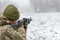 A military soldier takes aim with an automatic rifle and holds it in his mittens in winter