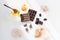 Milk and dark chocolate is scattered with slices on a white background, next to honey, orange peel and cocoa.
