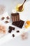 Milk and dark chocolate is scattered with slices on a white background, next to honey, orange peel and cocoa.