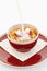 Milk falling on cornflakes with strawberry in red bowl on plate