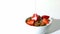 Milk falling in a wheat cereals and strawberries bowl